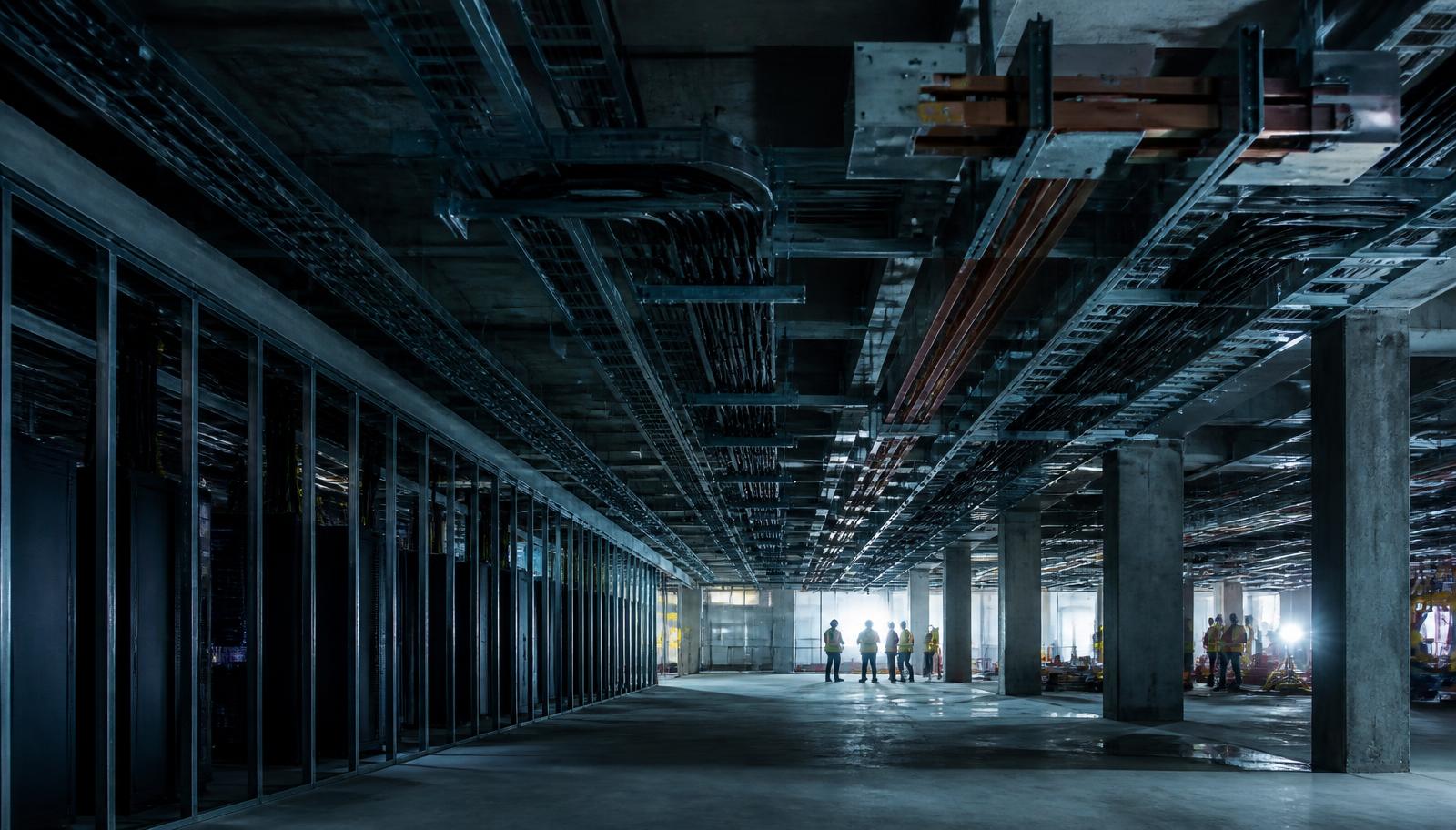 Construction workforce inside a data centre build, with cable trays and containment being installed
